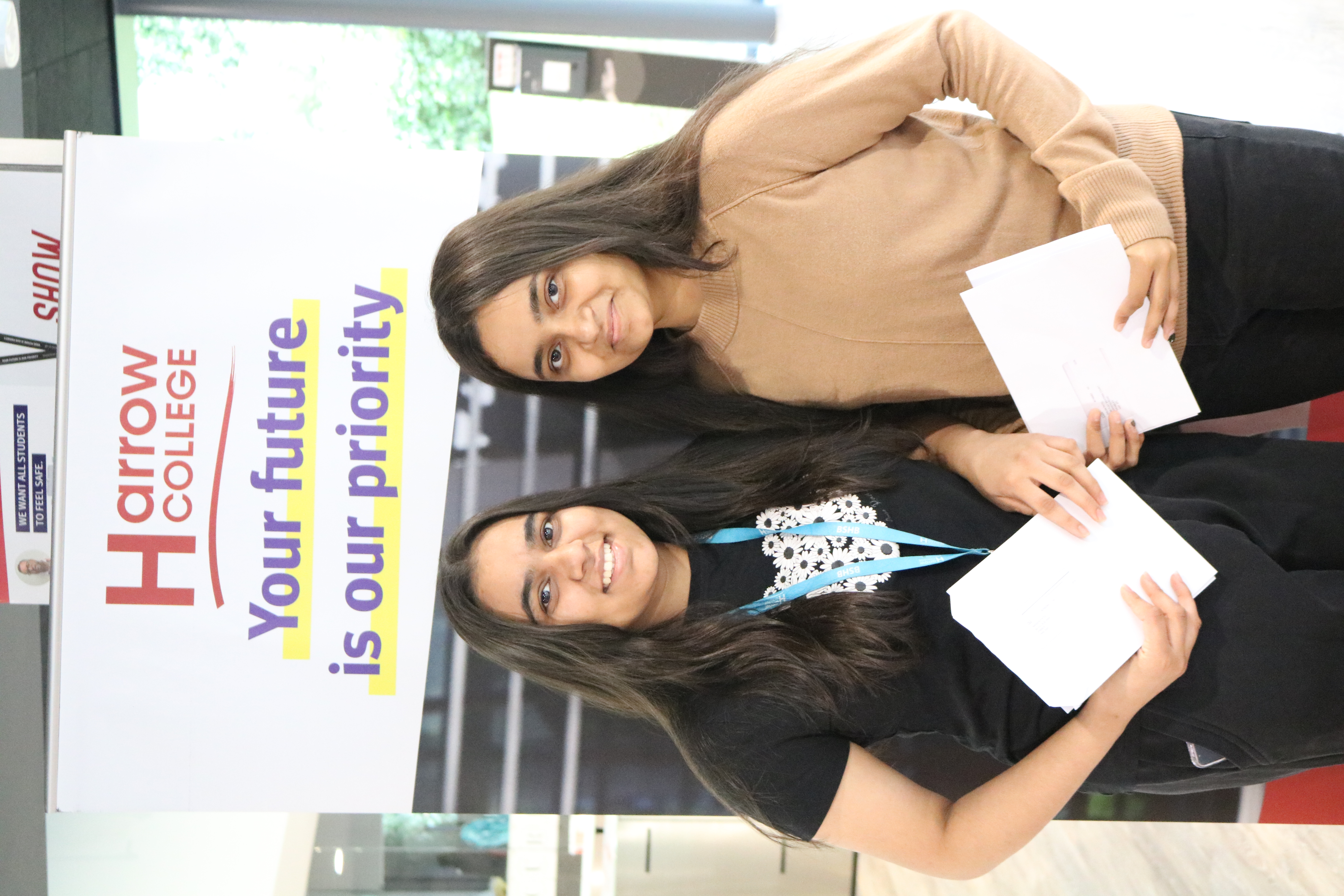 Two students, happily looking into the camera after opening their results