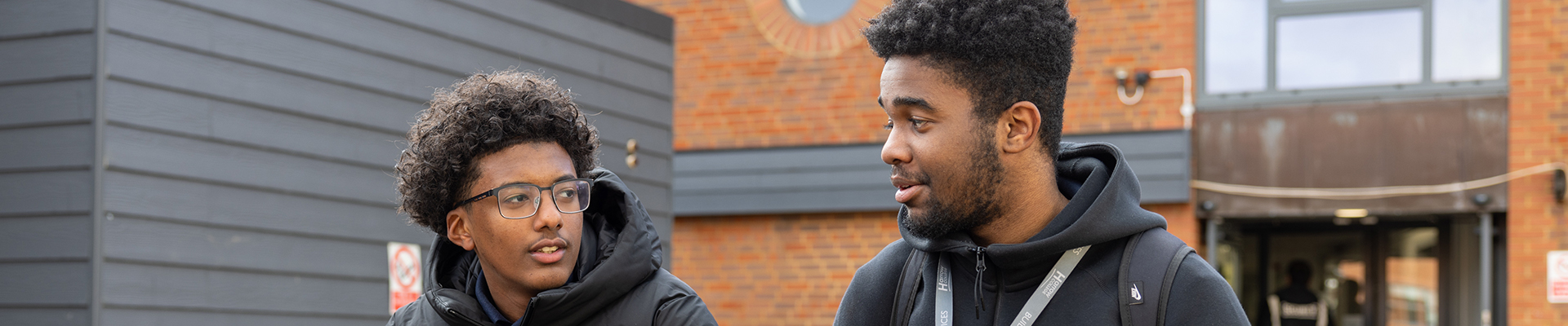 2 male Harrow Weald students talking to each other on a bench.