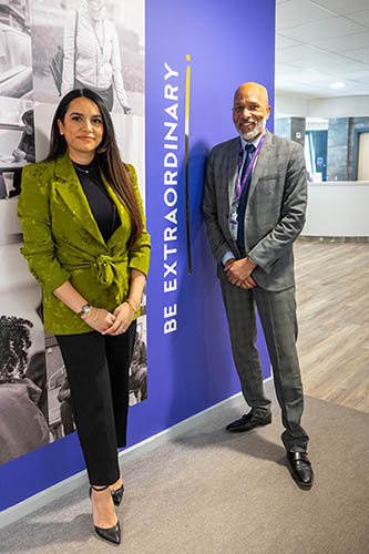 Former BBC The Apprentice winner and outstanding businesswoman Harpreet Kaur standing with Clive Hodge, Principal, Harrow College next to our Be Extraordinary signage.